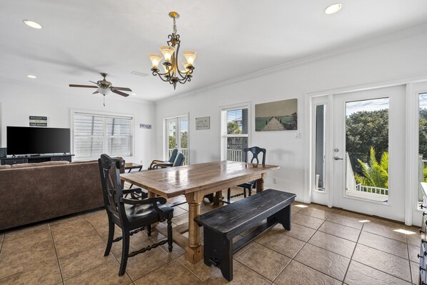 A spacious kitchen with a wooden table, chairs, a bench, a ceiling fan, and a TV. - Seabiscuit house at Kiva Dunes (Gulf Shores)