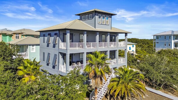 A multi-story building with balconies, surrounded by lush greenery and other buildings. - Seabiscuit house at Kiva Dunes (Gulf Shores)