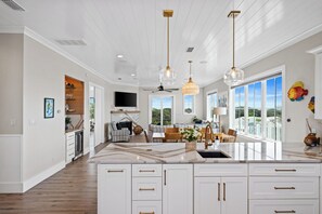 A spacious kitchen with a large island, pendant lighting, and a view to the outside.