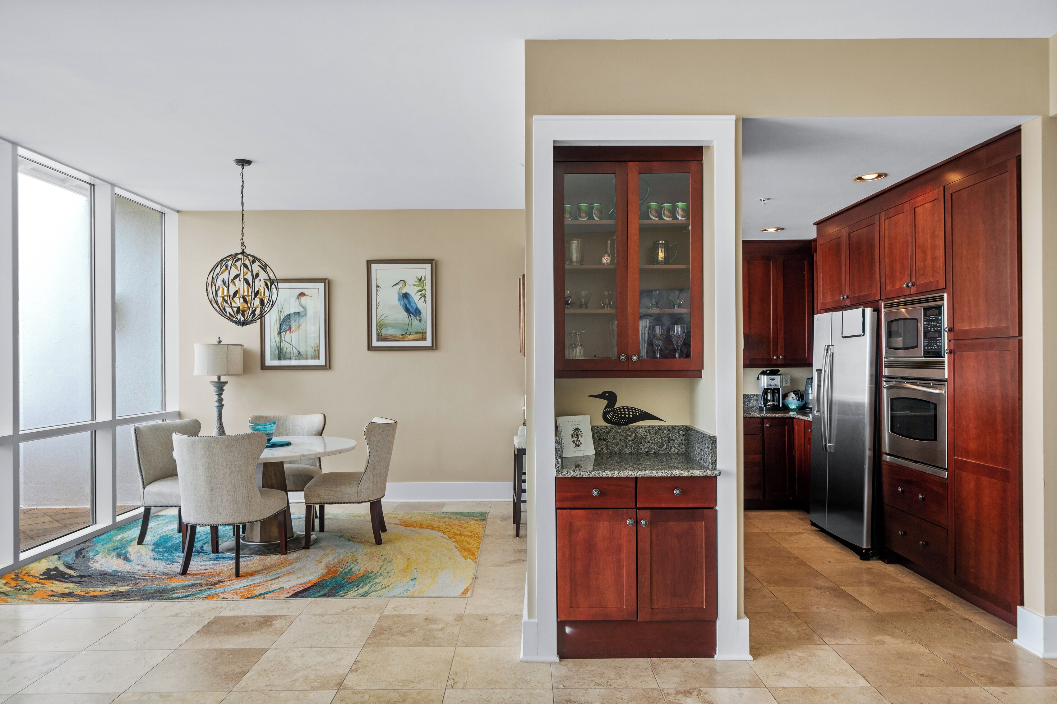 A modern kitchen with wooden cabinets, stainless steel appliances, and a dining area with a table and chairs.