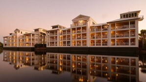 A waterfront hotel with multiple balconies and reflective water surfaces.