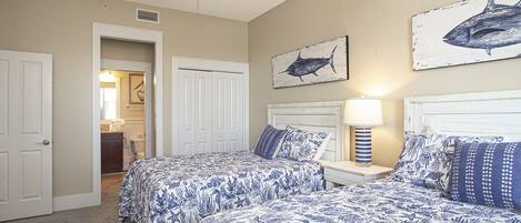 A bedroom with two beds, a ceiling fan, and artwork on the walls.
