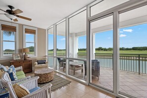Ein geräumiger Balkon mit Blick auf einen Golfplatz, ein Deckenventilator und Korbmöbel.