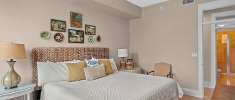 Un dormitorio con cama, mesita de noche, lámpara, silla y decoración en la pared.