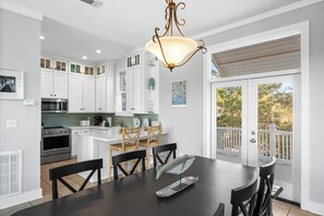 Une cuisine moderne avec des meubles blancs, une table à manger et une vue sur l’extérieur.