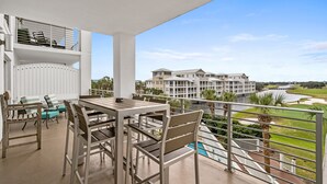 Ein Balkon mit Essbereich, Pool und Blick auf einen Golfplatz sowie Gebäude.
