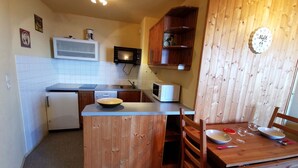 A compact kitchen with a microwave, a sink, and wooden cabinets. - 2-Room Cabin at the Foot of the Slopes - 4 Bunk Beds, Pets Allowed (Les Adrets-Prapoutel)