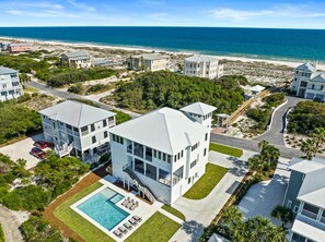 Una propiedad moderna frente a la playa con una piscina grande, varias edificaciones y vista al océano.