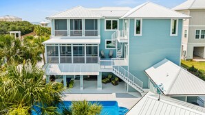 A two-story house with a pool, a covered patio, and a staircase leading to a balcony.