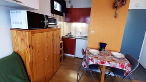 Cocina compacta con microondas, tostadora y lavabo. Se encuentra una mesa de comedor con sillas en la habitación.