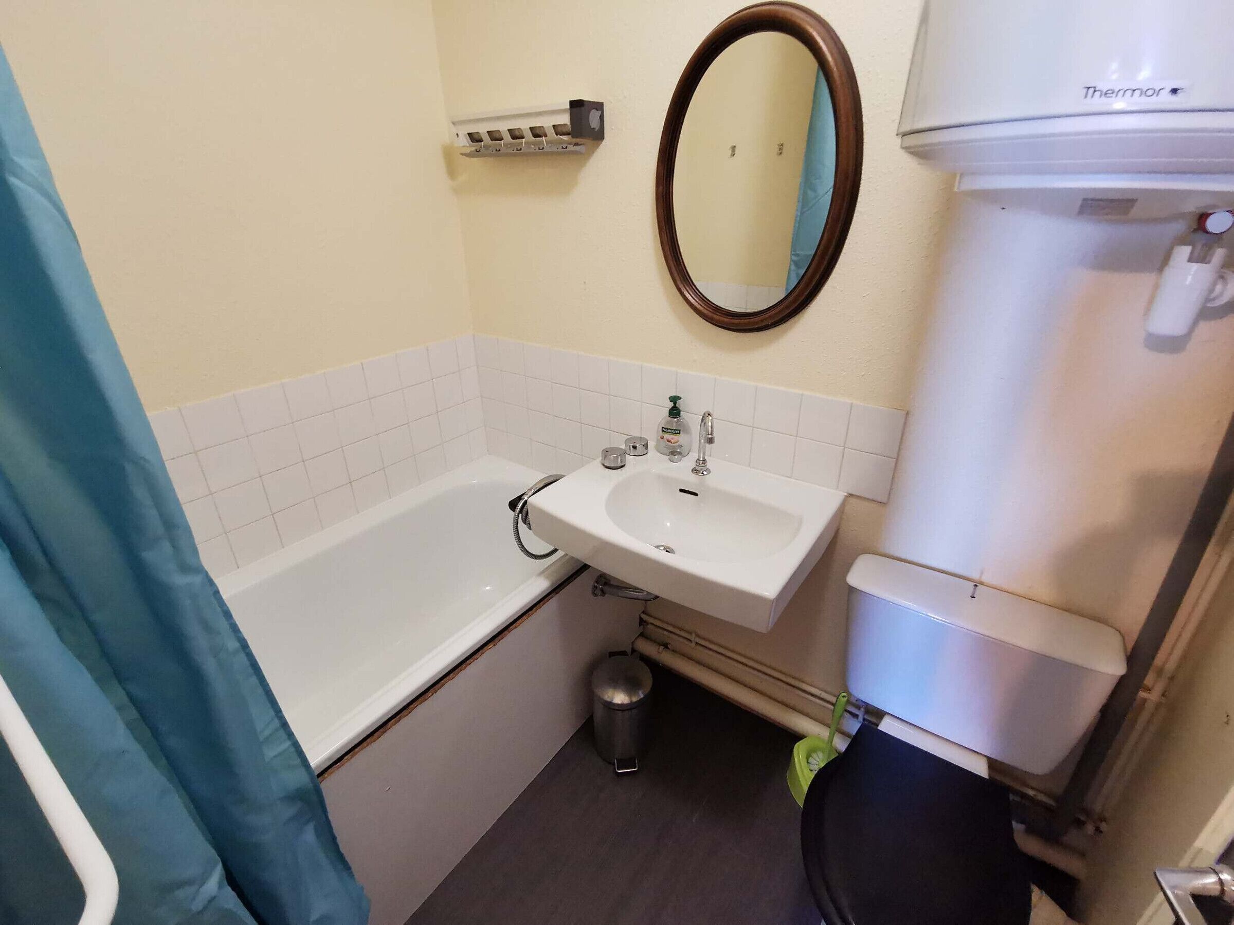 Une salle de bain avec une baignoire blanche, un lavabo et un miroir au-dessus, ainsi que des toilettes.
