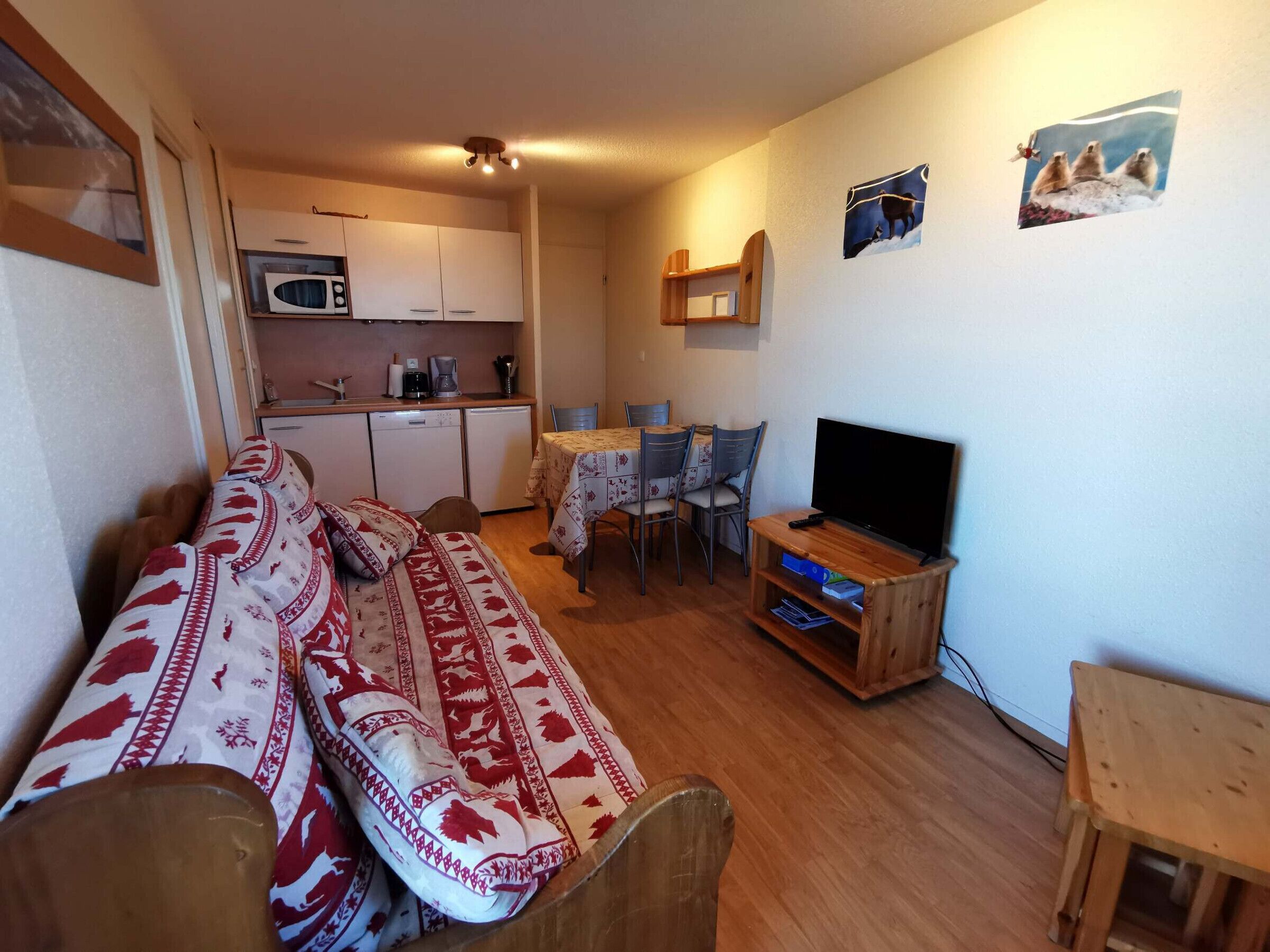 En kompakt opholdsstue med sofa, fjernsyn, spiseplads og tekøkken.