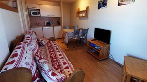 A compact living space with a sofa, a television, a dining area, and a kitchenette. - 2-Room Apt at the Foot of the Slopes, Sleeps 5 (Les Adrets-Prapoutel)