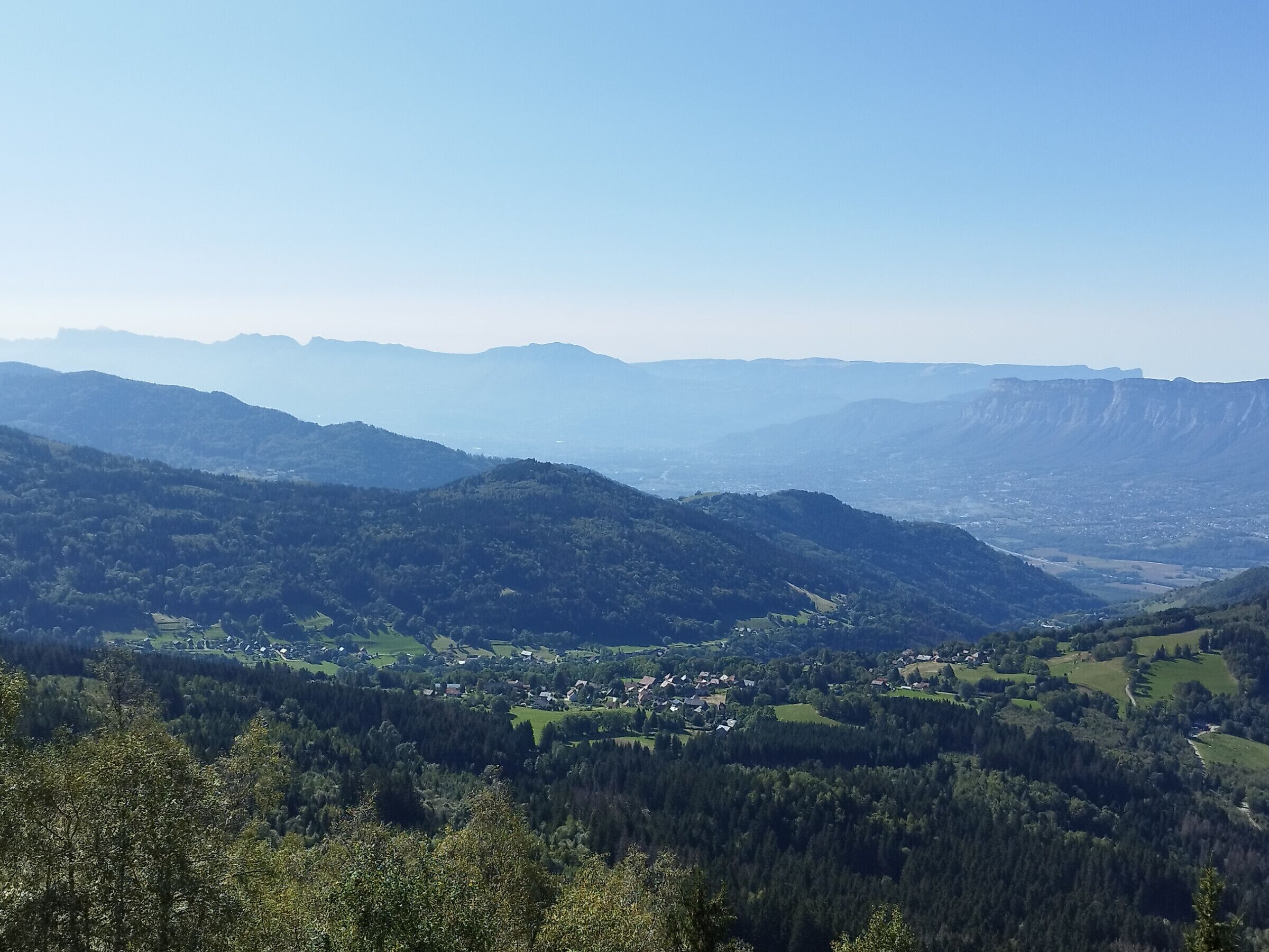 A panoramic view of a mountainous landscape with a valley below, featuring a small town nestled among the hills.