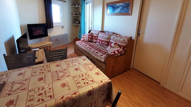 A cozy room with a bed, a television, a desk, and a window with curtains. - 2-Room Apt at the Foot of the Slopes, Sleeps 5 (Les Adrets-Prapoutel)