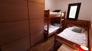 Een kamer met stapelbedden, een houten garderobe, een raam met uitzicht en een rode lamp.