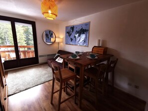 A dining area with a wooden table, chairs, a world map, a lamp, and a view of the outdoors.
