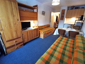 A compact room with a bed, a sofa, a television, a small table, and a kitchenette. - Studio at the foot of the slopes with balcony in Les Adrets-Prapoutel (Les Adrets-Prapoutel)