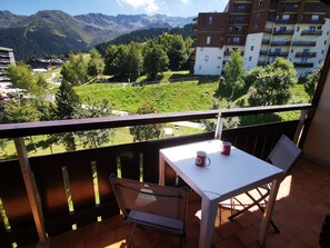 A balcony with a table and chairs, overlooking a mountainous landscape and a residential area. - 2 Rooms, ski-in/ski-out, near shops with balcony. Sleeps 6, no pets allowed (Les Adrets-Prapoutel)
