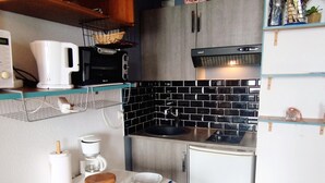 A compact kitchen with a coffee maker, toaster, and a small dining table with chairs. - Renovated studio near center, balcony and TV (Les Adrets-Prapoutel)