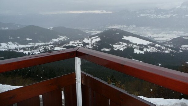 A view from a balcony with a wooden railing, overlooking a mountainous landscape with snow-covered peaks and valleys. - Renovated studio near center, balcony and TV (Les Adrets-Prapoutel)