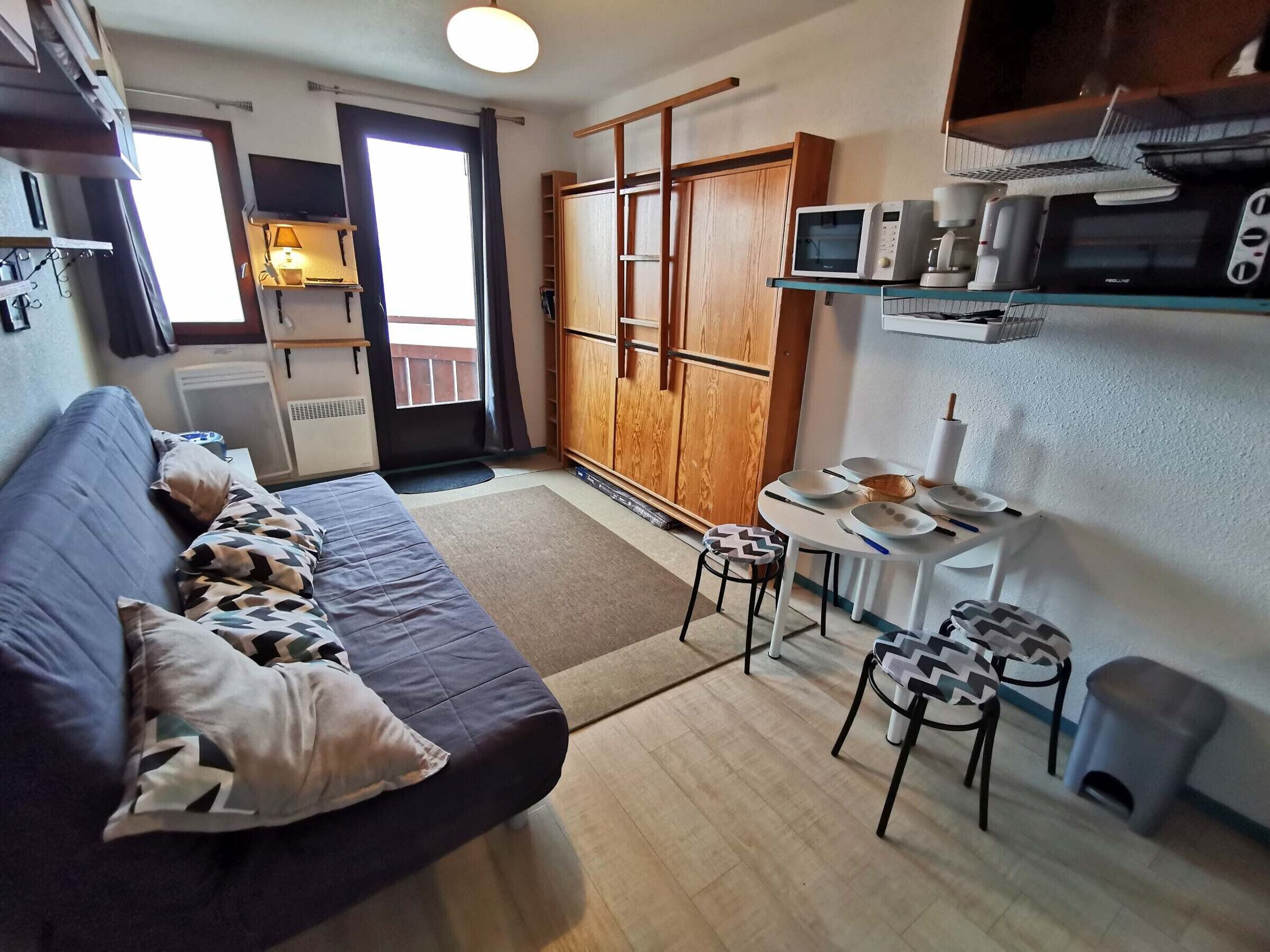 A compact living space with a sofa, a small dining table, and a kitchenette.