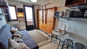 A compact living space with a sofa, a small dining table, and a kitchenette. - Renovated studio near center, balcony and TV (Les Adrets-Prapoutel)