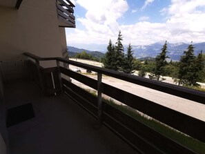 A balcony with a view of a mountain range and trees. - Apartment in Adrets-Prapoutel, 2 rooms, balcony, close to slopes and shops (Les Adrets-Prapoutel)