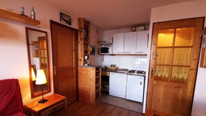 A compact kitchen with wooden cabinets, a microwave, and a small refrigerator. - Apartment in Adrets-Prapoutel, 2 rooms, balcony, close to slopes and shops (Les Adrets-Prapoutel)