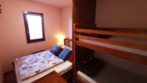 A bunk bed room with a window, a bedside lamp, and a wooden headboard. - Apartment in Adrets-Prapoutel, 2 rooms, balcony, close to slopes and shops (Les Adrets-Prapoutel)