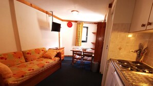 A compact room with a sofa, a dining table, and a kitchenette. - 2-room at the foot of the slopes, near lifts (Les Adrets-Prapoutel)