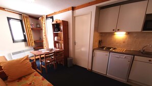 A compact hotel room with a kitchenette, a dining area, and a bed with floral bedding. - 2-room at the foot of the slopes, near lifts (Les Adrets-Prapoutel)