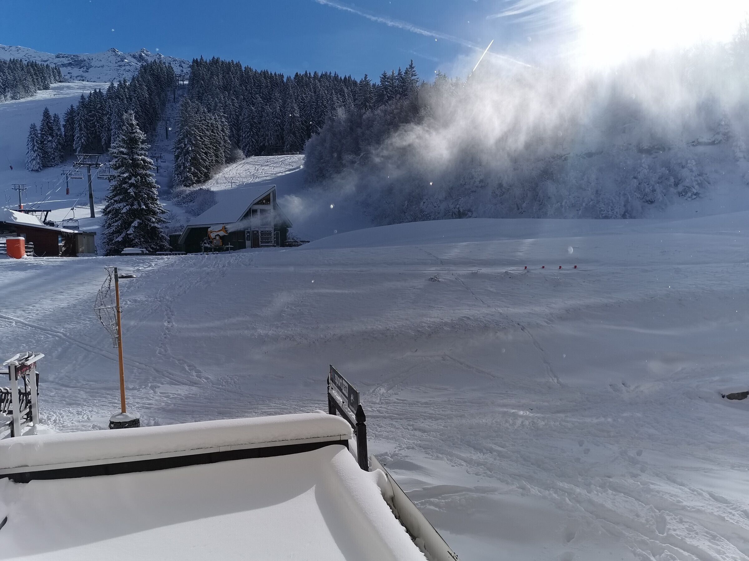 A snow-covered ski slope with a ski lift and a lodge in the background.