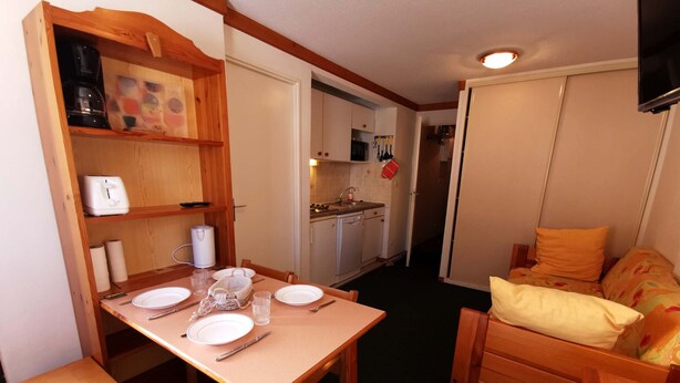 A compact living space with a dining table set for four, a kitchenette, and a small sofa. - 2-room at the foot of the slopes, near lifts (Les Adrets-Prapoutel)
