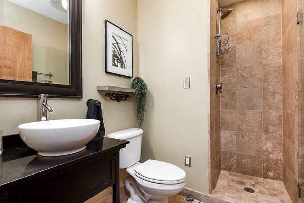 Une salle de bain avec un lavabo, des toilettes et une douche, le tout de couleur blanche.