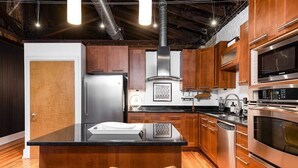 Une cuisine moderne avec des meubles en bois, des appareils en acier inoxydable et un îlot central doté de chaises.