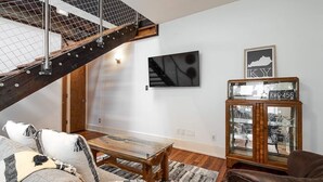 Un salon moderne avec une table basse en bois, un canapé, une vitrine et un escalier.