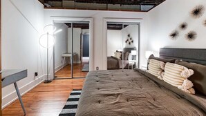 Une chambre avec un grand lit, un bureau et un luminaire moderne.