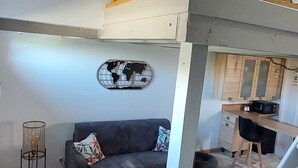 Ein Loft-Wohnbereich mit Holzboden, einer Treppe, einer Couch, einem Couchtisch und einem Essbereich mit Küchenzeile.