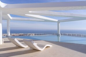 Un área de piscina moderna con vista despejada al océano y al paisaje urbano.