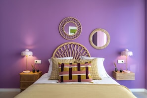 Un dormitorio con una cama, dos mesitas de noche, un cabecero y dos espejos fijados a la pared.