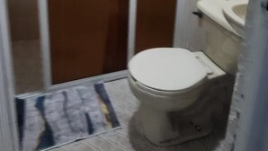 A small bathroom with a toilet, a sink, and a shower stall. - Casa Vazquez Anexo 1 (Pachuca)