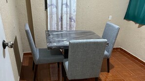 A dining area with a table and four chairs, a tiled floor, a door, and a curtain. - Casa Vazquez Anexo 1 (Pachuca)