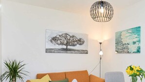 Una sala de estar moderna con sofá, una mesa de centro, una planta en maceta y obras de arte en las paredes.