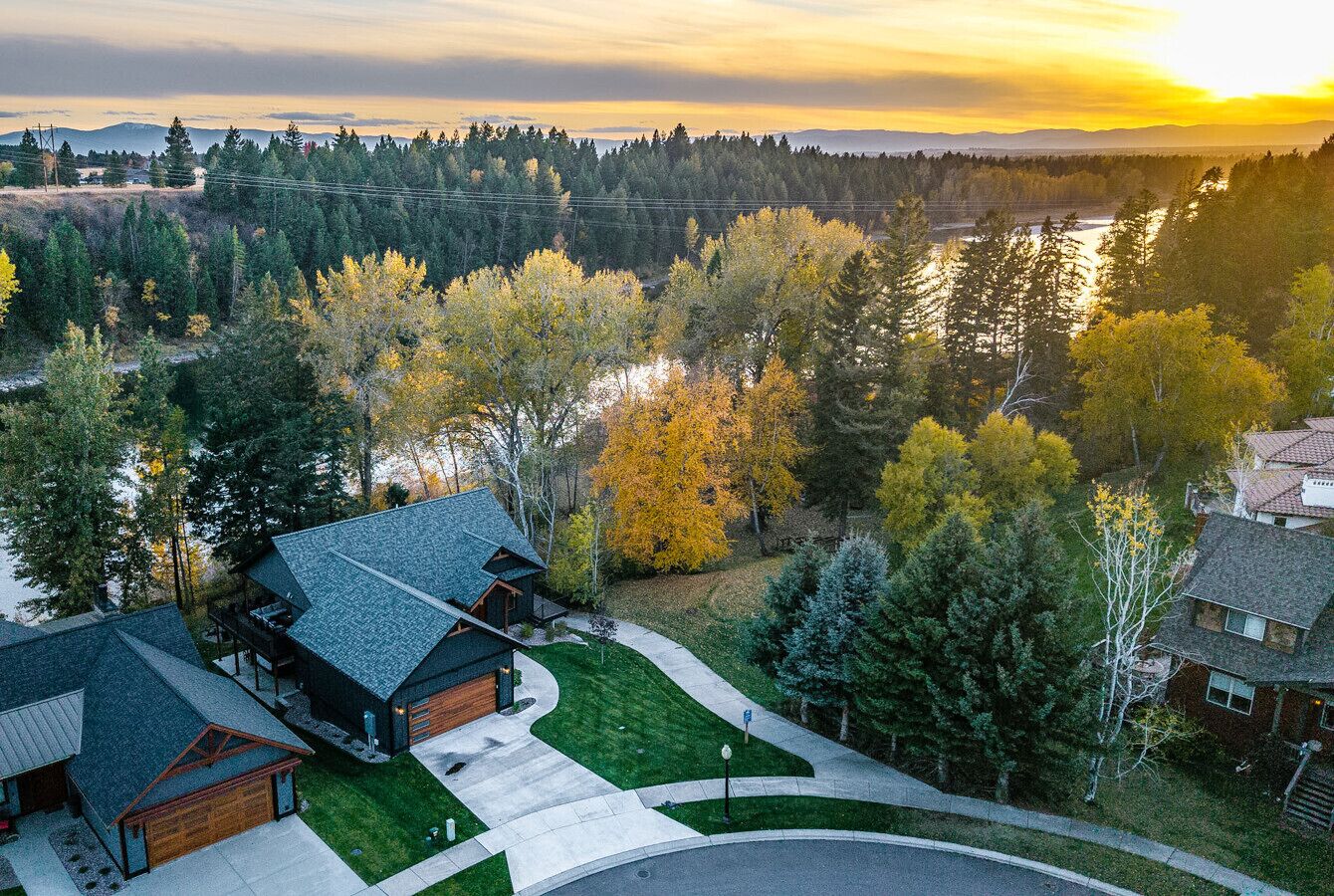 A residential area with houses, a driveway, and a river in the background.