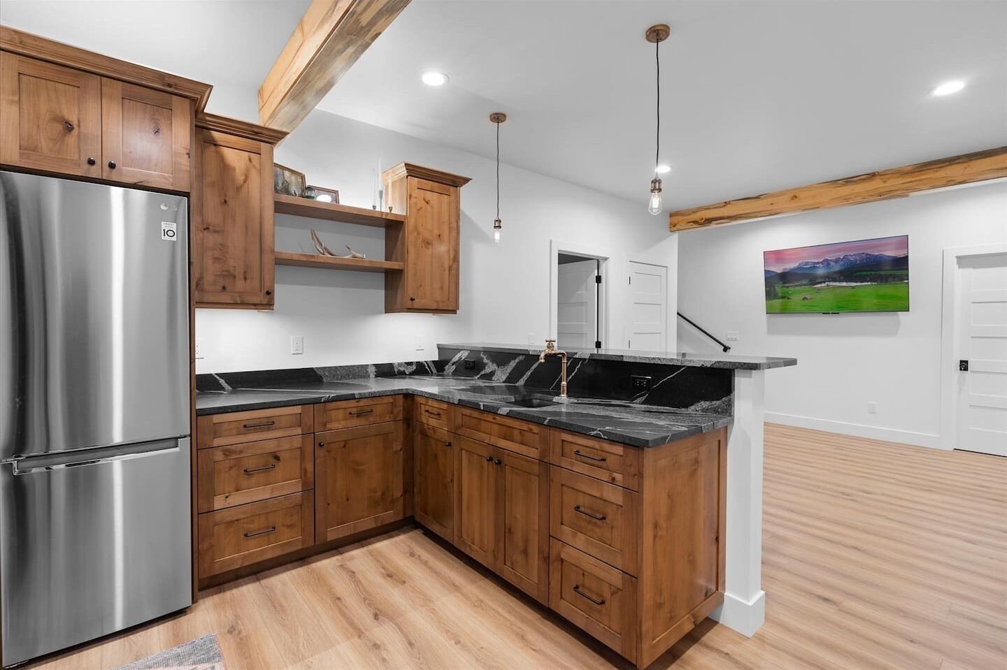 Eine moderne Küche mit Holzausbau, einem Edelstahlkühlschrank und einer Marmorarbeitsplatte.