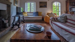 A cozy living room with a wooden table, a sofa, and a window with a view of greenery.