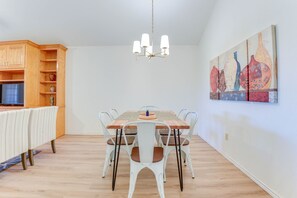 A dining area with a wooden table, white chairs, a chandelier, and a painting on the wall. - Relax Fireside! Poolside Oasis 3 Mi to Dtwn Sanger (Sanger)