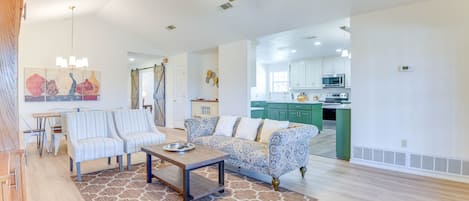 A spacious living room with a sofa, chairs, a coffee table, and a ceiling fan.