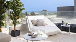 Un espace de détente extérieur moderne, avec un canapé blanc, une table ronde et une plante en pot.